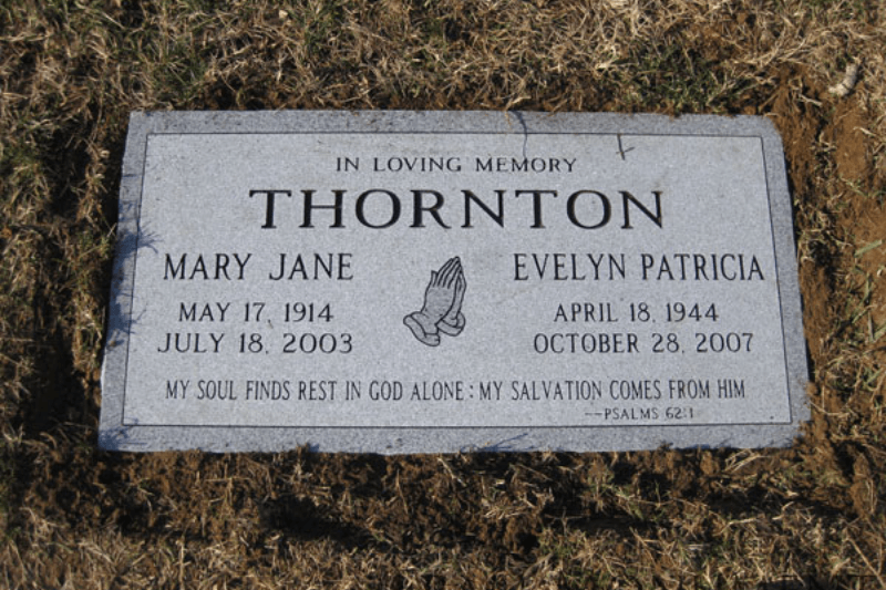 Granite flat grave marker with family names and religious inscription