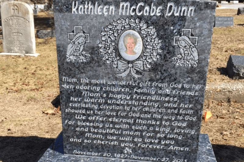 Granite memorial headstone with portrait, religious artwork, and a long tribute inscription