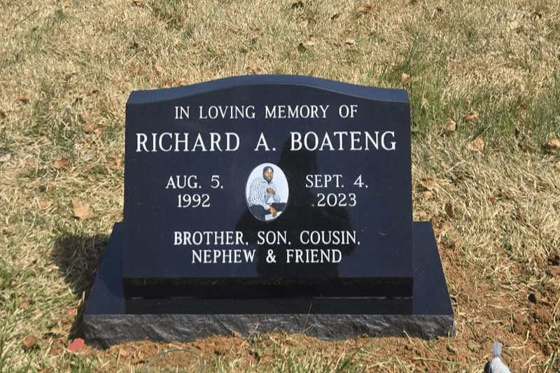 Low polished black granite headstone with an engraved inscription and oval memorial portrait