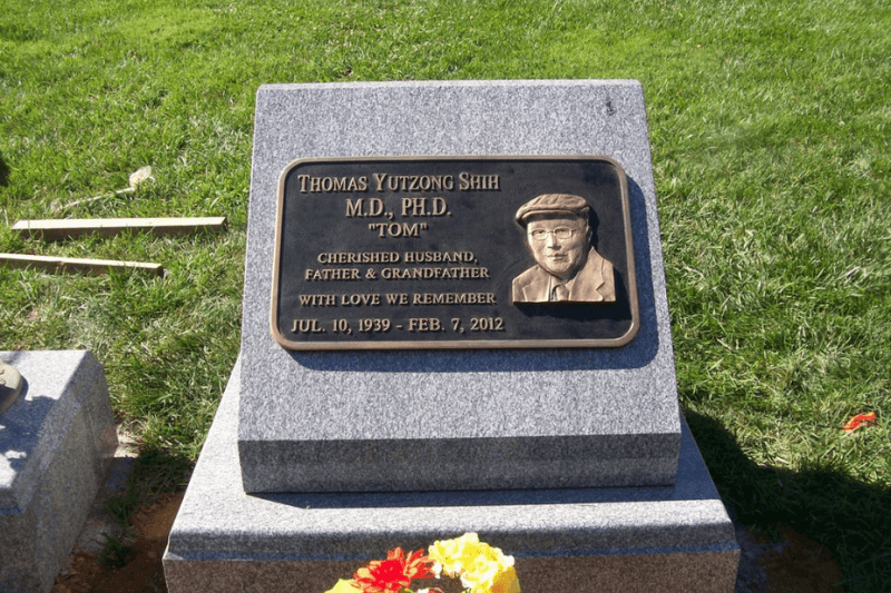 Slanted granite headstone with portrait plaque, engraved name, dates, and family tribute